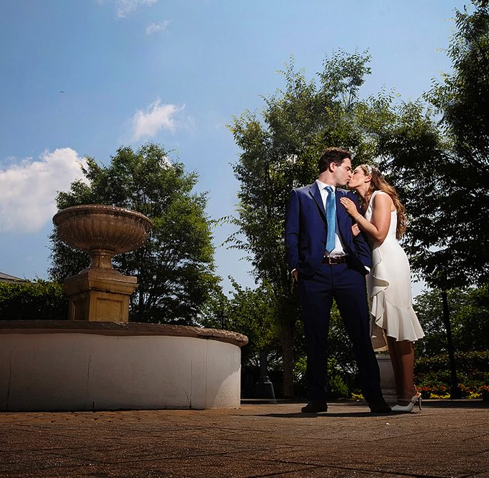 A bride and groom kissing outside by a fountain | Image Credit: Alyson Ridge