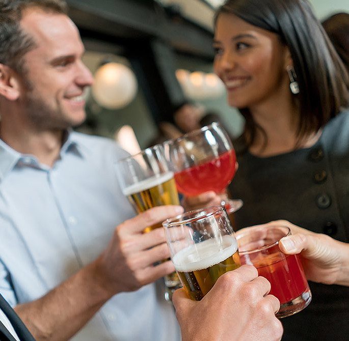 Man and woman looking at each other and toasting their drinks