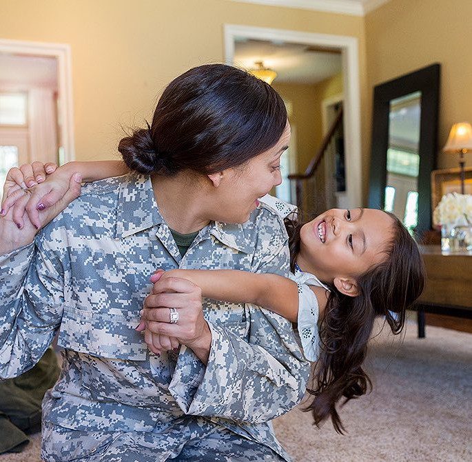 military mom holding her daughter inside a house